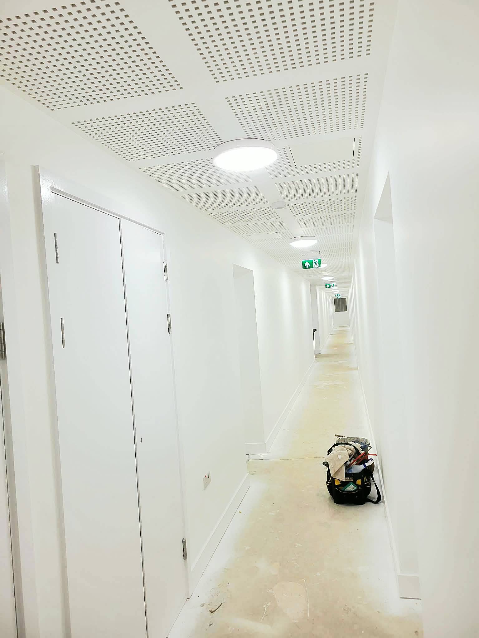 Commercial corridor with white walls and doors finished, dust sheets on the floor