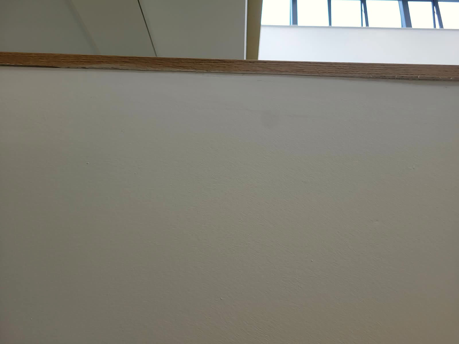 Smooth white wall finished under a timber capping rail