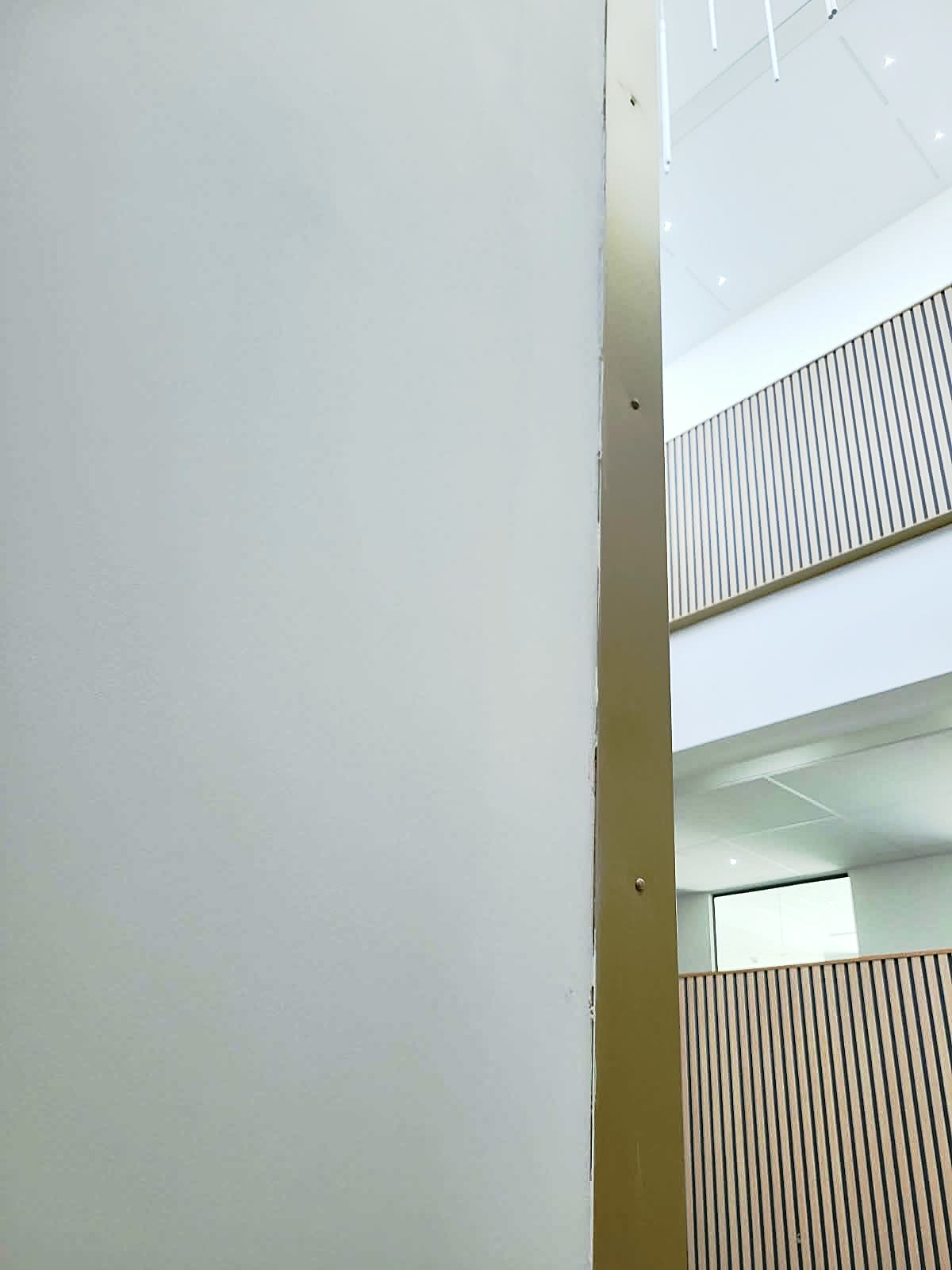 Crisp white painted column next to timber slatted panels